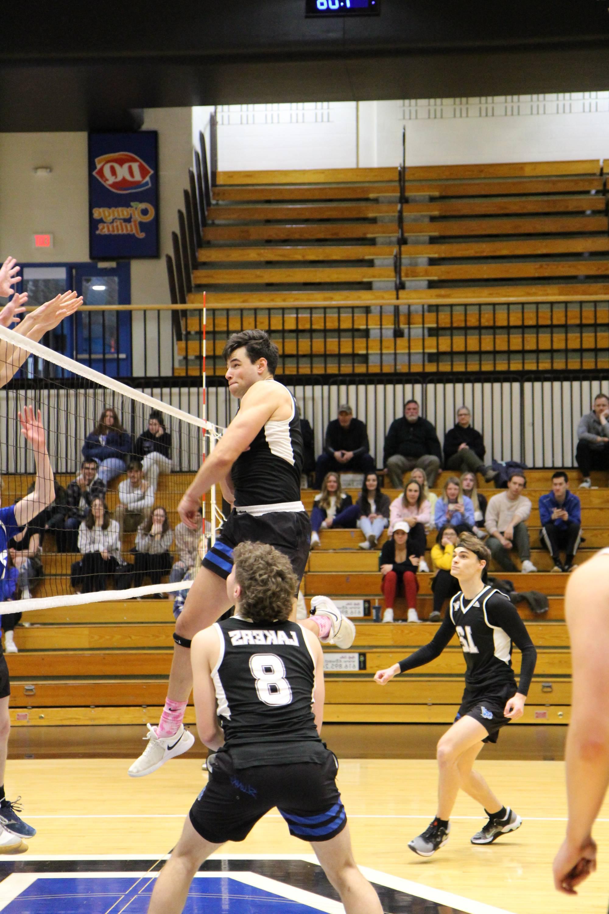 volleyball player finishing a hit with teammates surrounding him